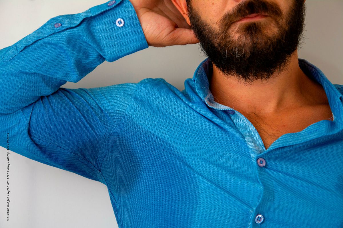
Mann in blauem Hemd mit großem Schwitzfleck unter dem Arm.